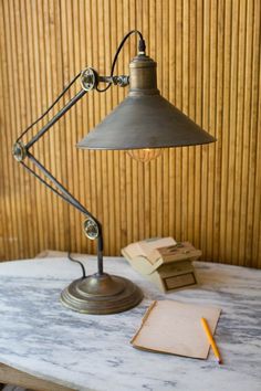 a desk lamp sitting on top of a table next to a stack of books and a notebook