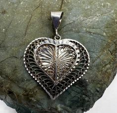 "Sterling Silver Filigree Heart Pendant made in Turkey 1.5\". This solid silver pendant features an openwork wire filigree design with chiseled textures. The pendant is hallmarked 925 Turkey on the bail. Condition is good, light tarnish, scuffs and scratches.  Thank you for looking!  Prices on shop items are fair and reasonable, no all prices are firm.  No reserves, all items sold as-is.  Please review photos and description carefully before purchasing.  Please let me now if you have any questio Silver Etched Heart Pendant Jewelry, Sterling Silver Filigree Heart Jewelry, Sterling Silver Heart Filigree Jewelry, Silver Heart-shaped Etched Jewelry, Etched Heart Silver Jewelry, Ornate Filigree Jewelry For Valentine's Day, Etched Heart Shaped Silver Jewelry, Silver Filigree Heart Pendant Jewelry, Silver Heart Pendant With Intricate Design