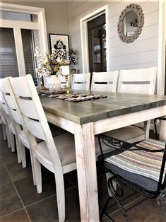 a dining room table with white chairs and a mirror on the wall in front of it