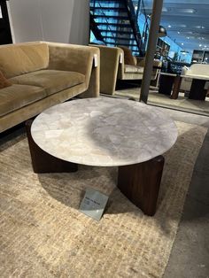 a living room with couches and a table on the floor in front of stairs