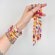 two hands holding bracelets made out of beads and other colorful beads on each wrist