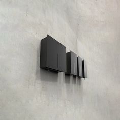 three black square shaped objects mounted to the side of a concrete wall in an industrial setting