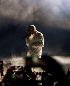 a man standing on top of a stage holding a microphone in front of a crowd