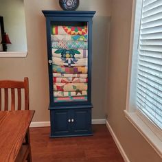 a tall blue cabinet with quilts on it