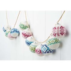 knitted ornaments hanging from strings on a white wall