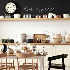 there is a clock above the kitchen table and chairs in front of the counter top