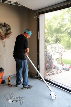 a man with a mop is cleaning the floor in front of an open garage door