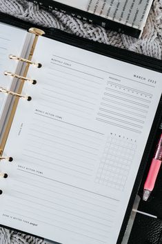 an open planner and pen sitting on top of a black binder