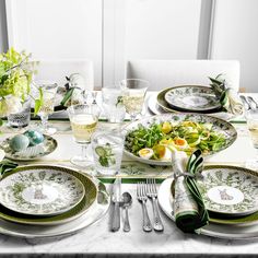 a table set with plates, silverware and green napkins for an easter dinner