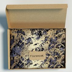 an open box containing a blue and gold marbled paper with the word florencek on it