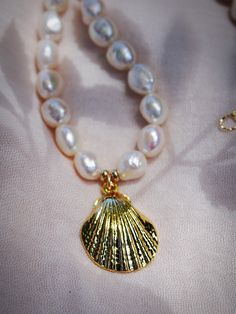 This chunky white freshwater pearl statement necklace evokes visions of Hawaii's white sandy beaches and reflects Hawaii's natural abundance. It features large freshwater pearls and a stunning gold shell pendant. This unique beauty is ready for you and your tropical escape.✦ DETAILS ✦✧ Name: Kawai (KAH wie) - coming from water.✧ Choose your length.✧ White Freshwater Pearl beads✧ Large Brass Seashell Pendant.✧ 14kt Gold Filled components and clasp.✧ All Ke Aloha Jewelry pieces come packaged thoug Elegant Pearl Chain Necklace With Shell, Elegant Pearl Charm Shell Necklace, Elegant Pearl Necklace With Shell And Pearl Charm, Elegant Shell Pearl Chain Necklace, Elegant Shell Pearl Necklace With Pearl Charm, Elegant Shell-shaped Necklace With Pearl Charm, Elegant Pearl Chain Necklace Made Of Shell, White Shell-shaped Pearl Pendant Jewelry, Shell-shaped Pearl Necklace With Pearl Pendant