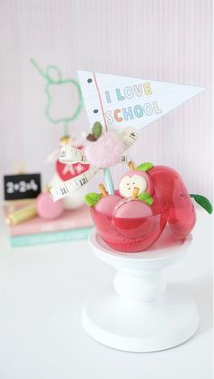 a small toy boat with an apple in it on top of a white pedestal next to a pink wall