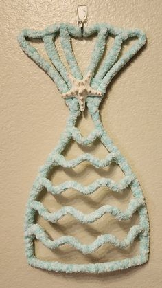 a piece of art made out of yarn hanging on a wall in the shape of a vase