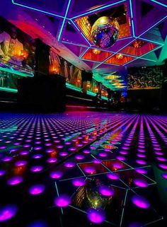 the floor is lit up with purple and green lights in an indoor space that has disco balls all over it