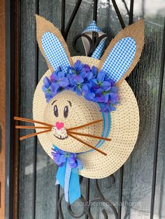 a straw hat shaped like a bunny with blue flowers on it's head and ears