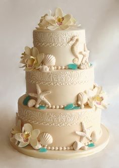 a three tiered cake decorated with seashells and flowers