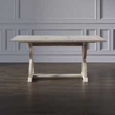 a wooden table sitting on top of a hard wood floor next to a white wall