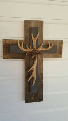 a cross made out of wood with antlers hanging on it's side wall