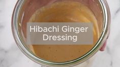 a person holding a glass jar filled with liquid and the words hibaachii ginger dressing