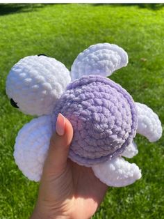 a hand is holding a crocheted flower in the grass