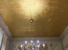 a chandelier hanging from the ceiling in a room with gold paint on it