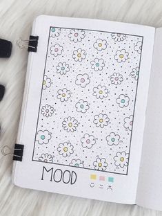 an open notebook with flowers and the word mood written on it next to some markers