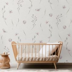 a baby crib next to a wall with flowers on it