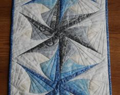 a blue and white quilted star on top of a wooden table