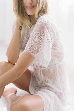 a woman sitting on top of a bed wearing a white dress