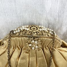 "An eye-catching vintage evening bag in shimmering gold! Likely from the late 1930s/early 1940s. The tops of the pleats show wear at the edge of the gathers. It is lined in a pale tawny satin with internal pockets. Interior is clean, but does have a few small snags. Interior tag for \"Ed B. Robinson\". Chain strap is tarnished. Note that the photos show the bag stuffed with tissue. There are a few light horizontal fold in the gold fabric from improper storage (see photos.)" Vintage Evening Bag For Vintage Events, Classic Cream Evening Clutch, Classic Beige Evening Bag, Vintage Evening Bag For Events, Classic Gold Clutch Evening Bag, Elegant Clutch Evening Bag For Vintage Events, Antique Clutch Evening Bag For Vintage Events, Antique Style Clutch For Vintage Events, Gold Vintage Bag For Events