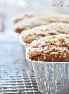 some muffins are sitting in tin foil on a cooling rack, ready to be eaten