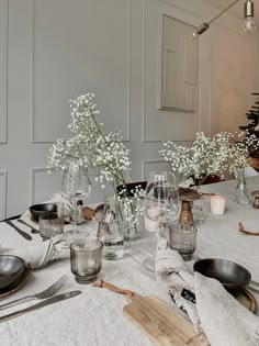 the table is set with silverware and glass vases filled with baby's breath flowers