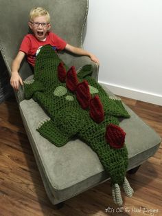 a young boy sitting on a couch made to look like a crocheted alligator