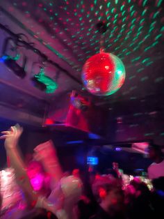 people are dancing in a club with disco lights on the ceiling and colorful balls hanging from the ceiling