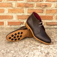 a pair of brown shoes sitting on top of a cement floor next to a brick wall