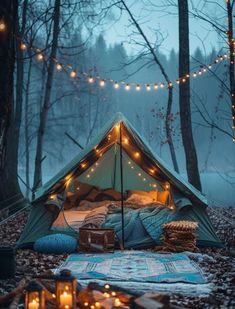 a tent is set up in the woods with candles