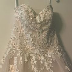 a dress hanging on a hanger next to a white wall with flowers and leaves