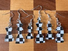 four pieces of black and white chess set on a checkered tablecloth with silver earwires