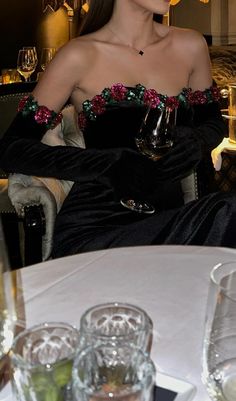 a woman sitting at a table with wine glasses