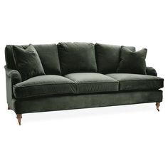 a green velvet couch with four pillows on it's arms and legs, against a white background