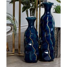 two blue vases sitting next to each other in front of a potted plant