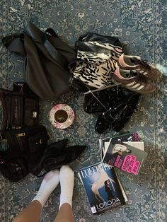 a woman's feet are on the floor next to purses and other items