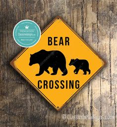 a yellow bear crossing sign sitting on top of a wooden table next to a sticker