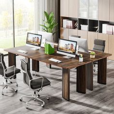 an office desk with two monitors on it and four chairs in front of the desk