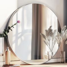 a mirror sitting on top of a table next to a vase with flowers in it