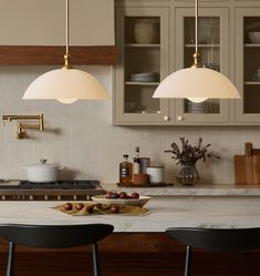 two pendant lights hanging over a kitchen island