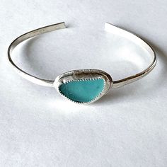 a close up of a bracelet on a white surface with a blue stone in the middle