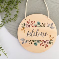 a wooden sign with the word adeline painted on it next to a plant