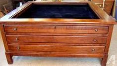 an old wooden chest with black velvet on the top and bottom drawer, sitting in a room