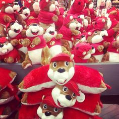 many stuffed animals are on display in a store with red and white hats, one is wearing a santa claus hat